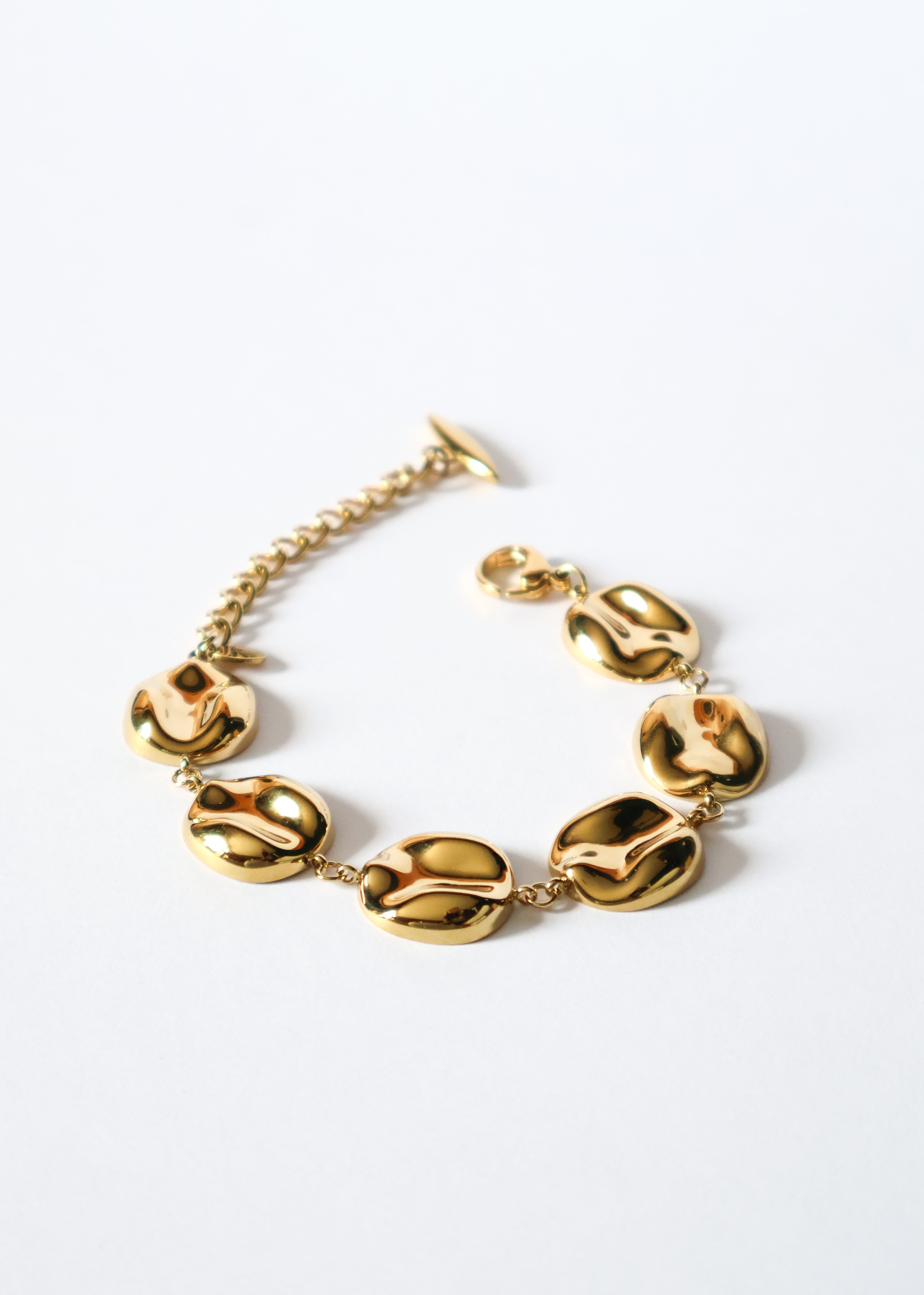 Bracelet en acier inoxydable doré/or composé de maillons ronds incurvés et martelés.