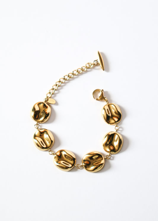 Bracelet en acier inoxydable doré/or composé de maillons ronds incurvés et martelés.